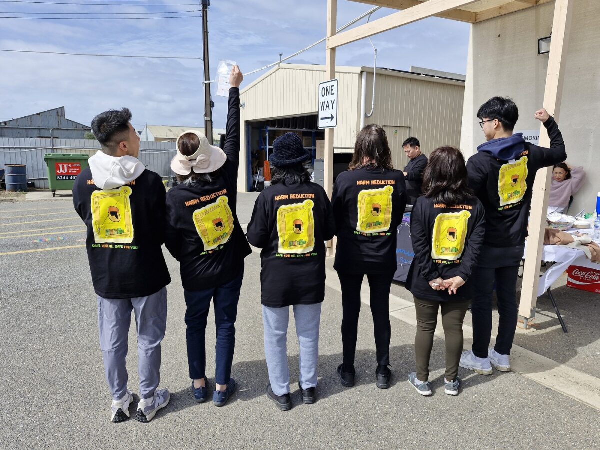 Fiona and community members in our ATSI Harm Reduction T-shirts, holding naloxone flyers