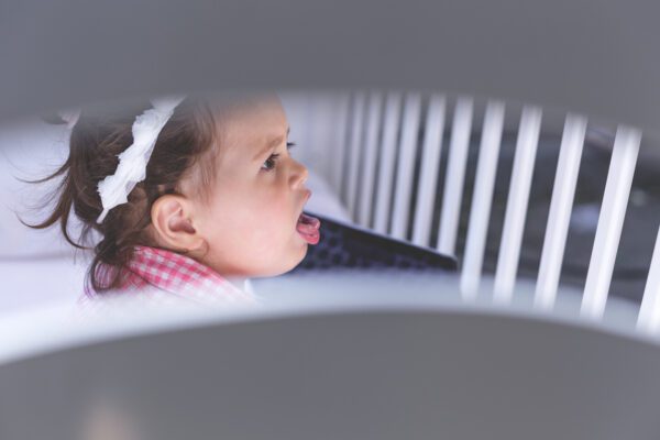 baby is sitting in a crib and coughing